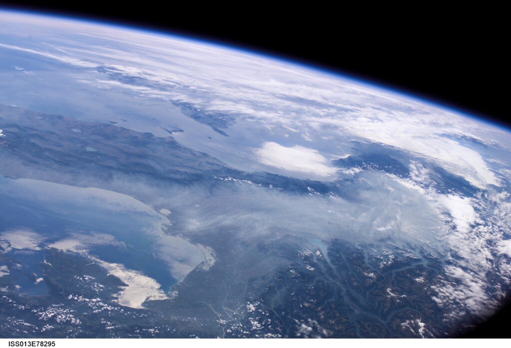 View from space of Earth's curvature, showing vast landscapes and swirling white clouds over blue oceans, conveying a serene and majestic atmosphere.